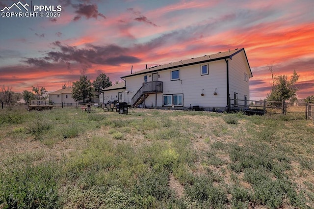 back of property at dusk with fence and stairs