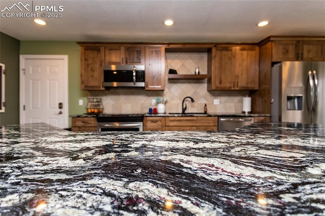 kitchen featuring tasteful backsplash, sink, dark stone counters, and appliances with stainless steel finishes