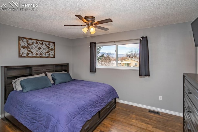 bedroom with a textured ceiling, dark hardwood / wood-style floors, and ceiling fan