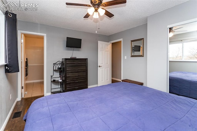 bedroom featuring ceiling fan, ensuite bathroom, dark wood-type flooring, and a textured ceiling