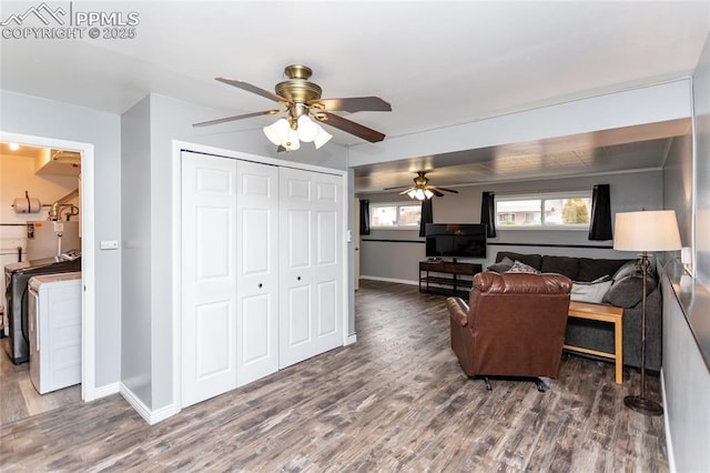 living room featuring washing machine and dryer, ceiling fan, and dark hardwood / wood-style floors