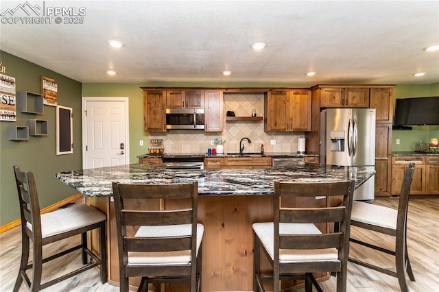 kitchen featuring a breakfast bar, stainless steel appliances, a spacious island, sink, and light hardwood / wood-style floors