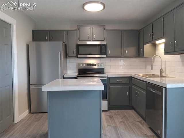 kitchen with gray cabinetry, a kitchen island, sink, and stainless steel appliances