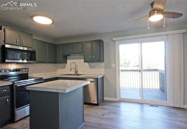 kitchen featuring tasteful backsplash, stainless steel appliances, ceiling fan, sink, and a center island