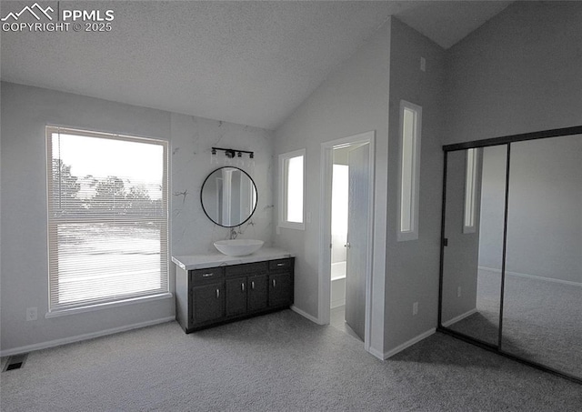 bathroom with a washtub, vanity, plenty of natural light, and lofted ceiling