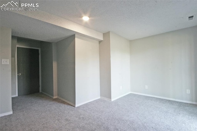 unfurnished room with carpet and a textured ceiling