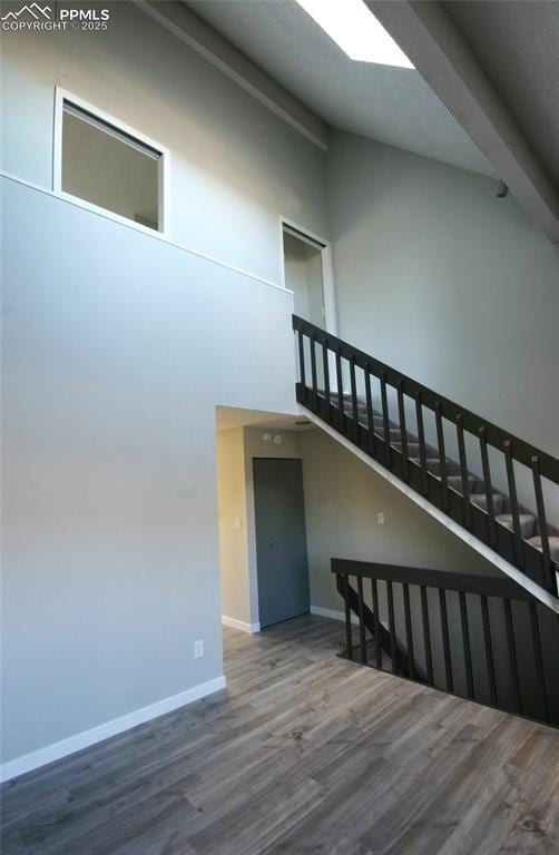 staircase featuring beamed ceiling, high vaulted ceiling, and wood-type flooring