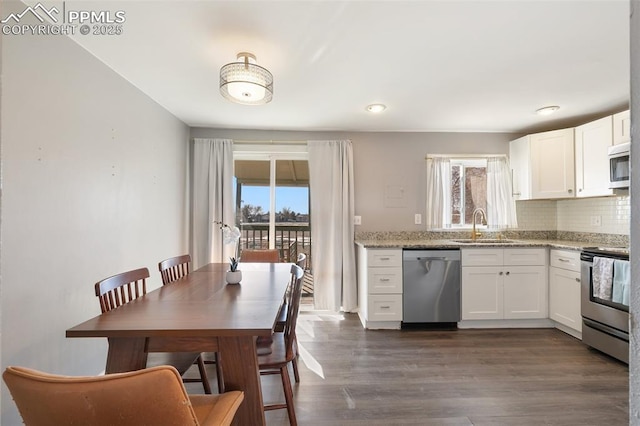 kitchen featuring appliances with stainless steel finishes, sink, light stone counters, and white cabinetry