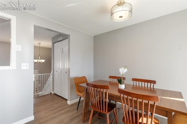 dining space with hardwood / wood-style flooring and a notable chandelier