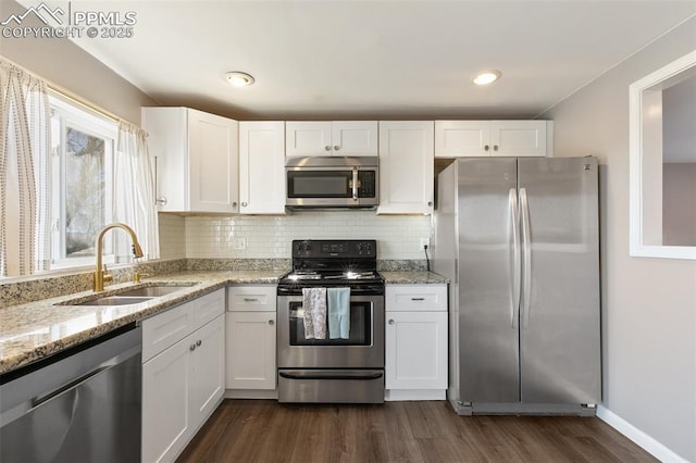 kitchen featuring stainless steel appliances, white cabinets, light stone counters, and sink