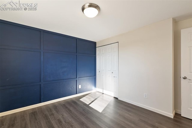 unfurnished bedroom with dark wood-type flooring and a closet