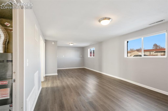 spare room featuring dark wood-type flooring and a healthy amount of sunlight