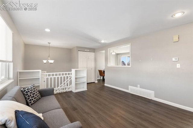 living room featuring dark wood-type flooring, a wealth of natural light, and a notable chandelier