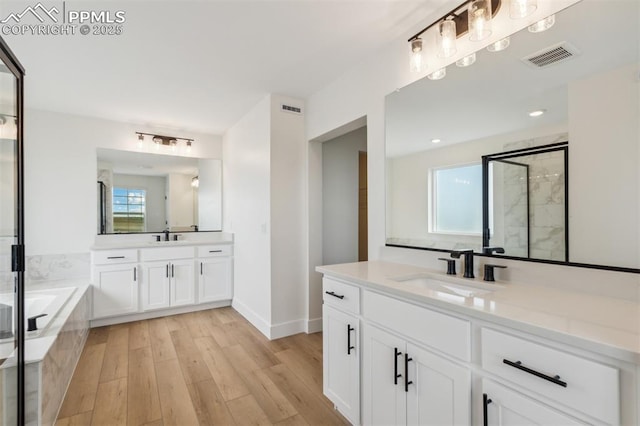 bathroom featuring hardwood / wood-style floors, vanity, and separate shower and tub