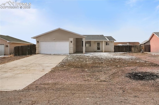 ranch-style home with a garage, fence, driveway, and stucco siding