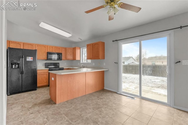 kitchen featuring light countertops, a sink, vaulted ceiling, a peninsula, and black appliances