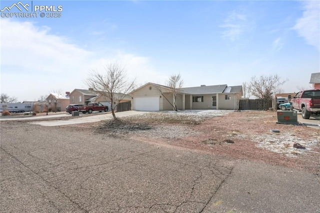 view of front of house with a residential view, fence, driveway, and an attached garage