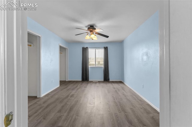 unfurnished room with baseboards, a ceiling fan, and wood finished floors