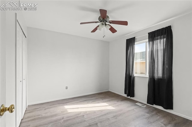 spare room featuring light wood-type flooring, visible vents, ceiling fan, and baseboards