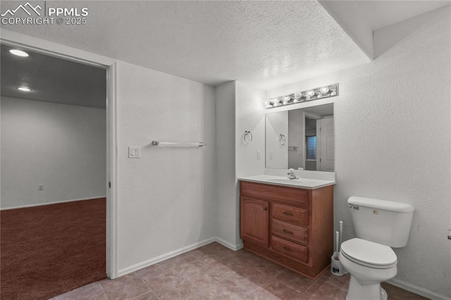 bathroom featuring a textured wall, toilet, vanity, a textured ceiling, and baseboards