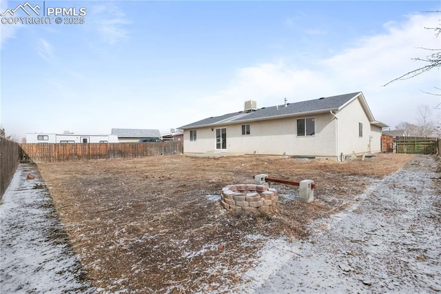 back of property with an outdoor fire pit, central AC unit, a fenced backyard, and stucco siding