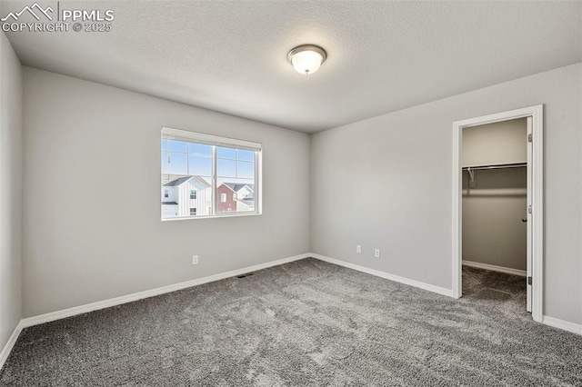 unfurnished bedroom with carpet, a textured ceiling, a walk in closet, and a closet