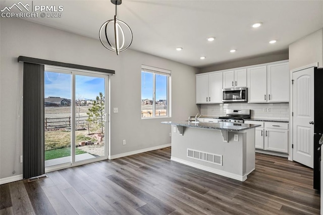 kitchen featuring white cabinetry, pendant lighting, stone countertops, a kitchen island with sink, and appliances with stainless steel finishes