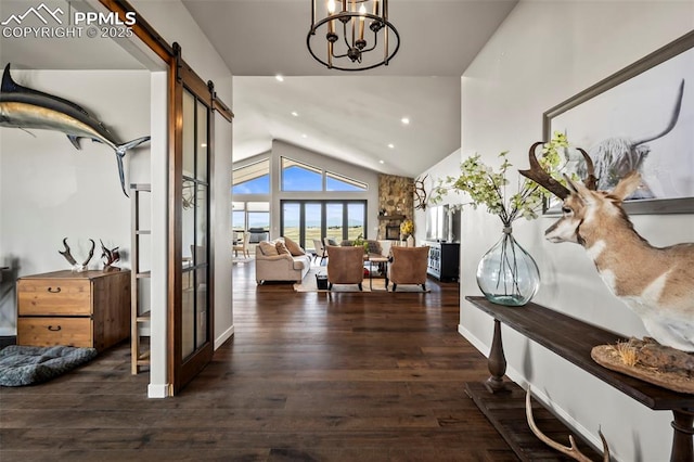 hallway with a barn door, dark wood-type flooring, vaulted ceiling, and a notable chandelier