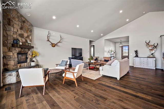 living room featuring a stone fireplace, high vaulted ceiling, dark hardwood / wood-style floors, and an inviting chandelier