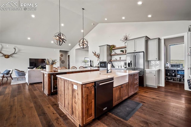 kitchen with sink, backsplash, pendant lighting, a kitchen island with sink, and appliances with stainless steel finishes