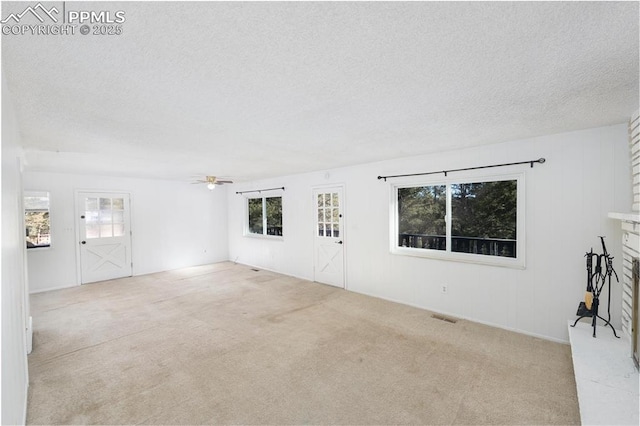 unfurnished living room with a fireplace, light carpet, plenty of natural light, and ceiling fan