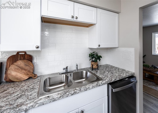 kitchen featuring dishwasher, sink, decorative backsplash, light stone countertops, and white cabinetry