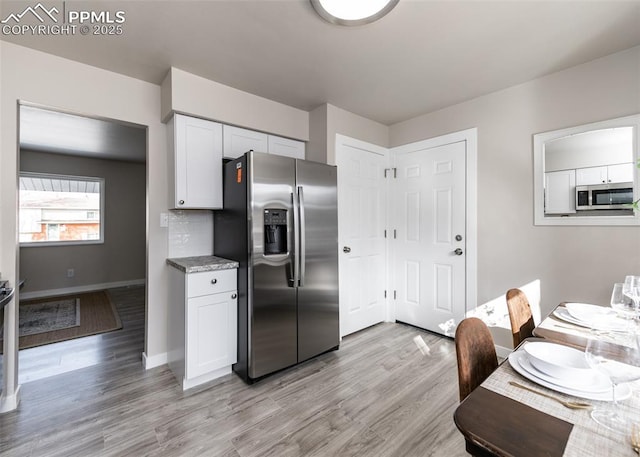 kitchen featuring white cabinets, stainless steel appliances, light hardwood / wood-style flooring, and tasteful backsplash