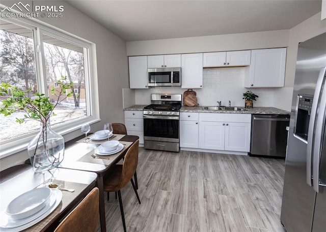 kitchen with stone counters, white cabinets, sink, appliances with stainless steel finishes, and tasteful backsplash