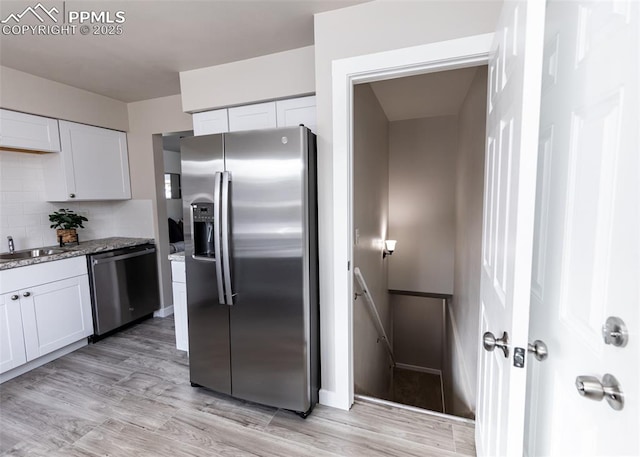 kitchen with stone counters, stainless steel appliances, white cabinetry, and light hardwood / wood-style flooring