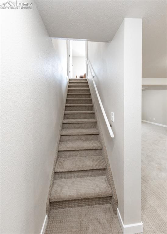 stairway with carpet and a textured ceiling