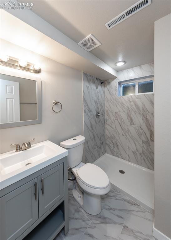 bathroom with vanity, toilet, and tiled shower