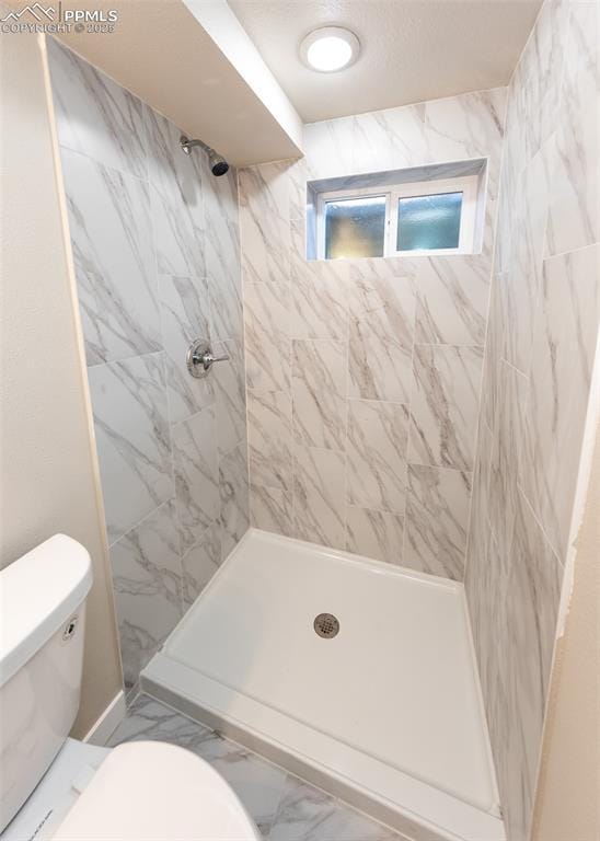 bathroom featuring toilet and a tile shower