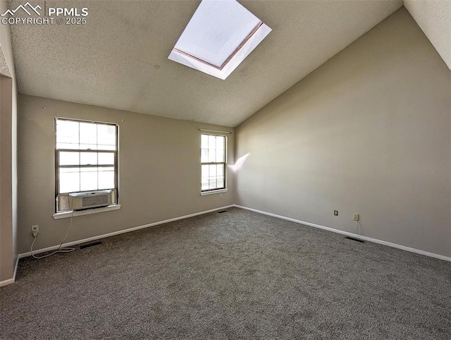 carpeted empty room with cooling unit and lofted ceiling with skylight