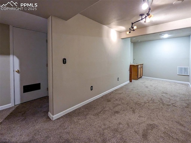 basement with carpet flooring and rail lighting