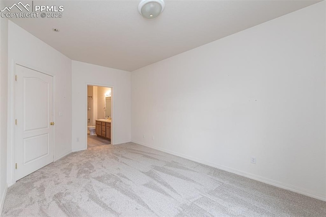 unfurnished bedroom featuring ensuite bathroom and light colored carpet