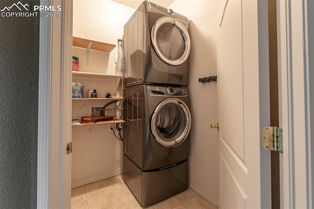 laundry room featuring light tile patterned floors and stacked washer / drying machine