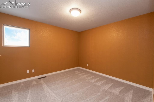 unfurnished room with a textured ceiling and carpet floors