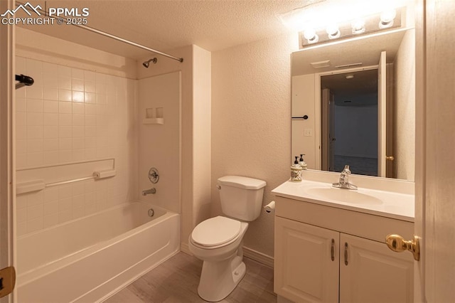 full bathroom with vanity, tiled shower / bath combo, a textured ceiling, hardwood / wood-style floors, and toilet