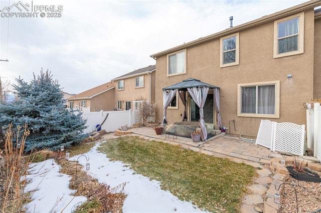 snow covered back of property featuring a gazebo and a patio