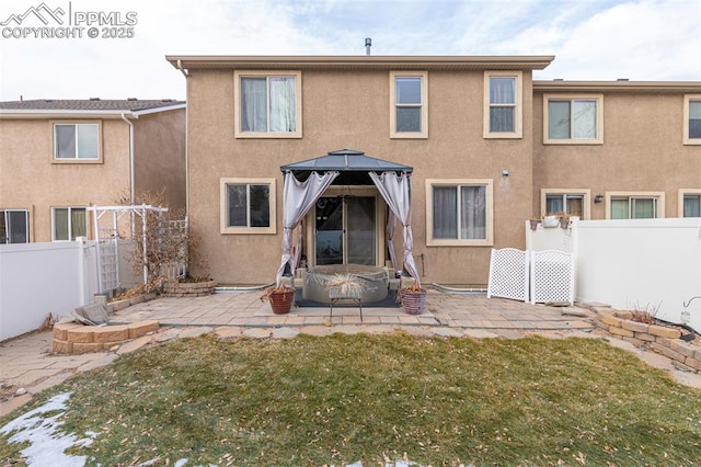 rear view of property featuring a gazebo, a yard, and a patio