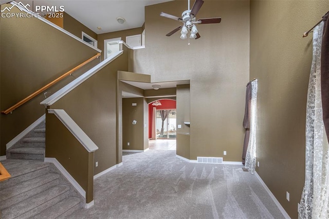 interior space with carpet, ceiling fan, and a high ceiling