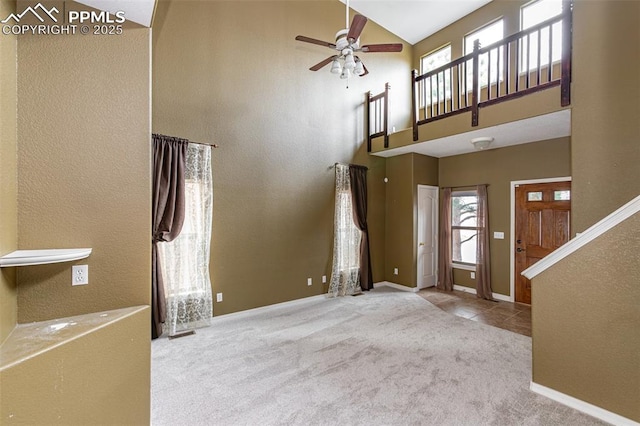 carpeted foyer entrance featuring ceiling fan and a high ceiling