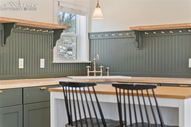 kitchen with hanging light fixtures, butcher block counters, and sink