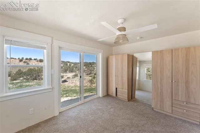 unfurnished bedroom featuring multiple windows, ceiling fan, and light colored carpet